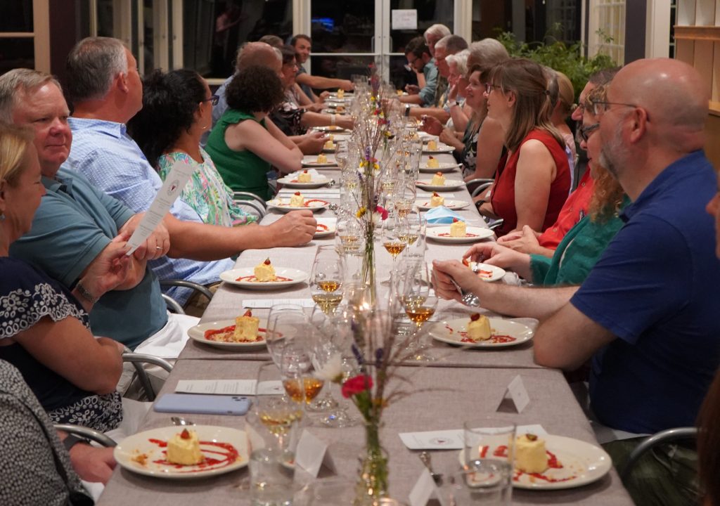 Guests seated at long table with dessert course